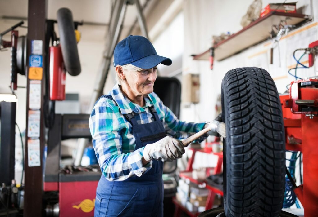 Senior female mechanic repairing a car in a garage.